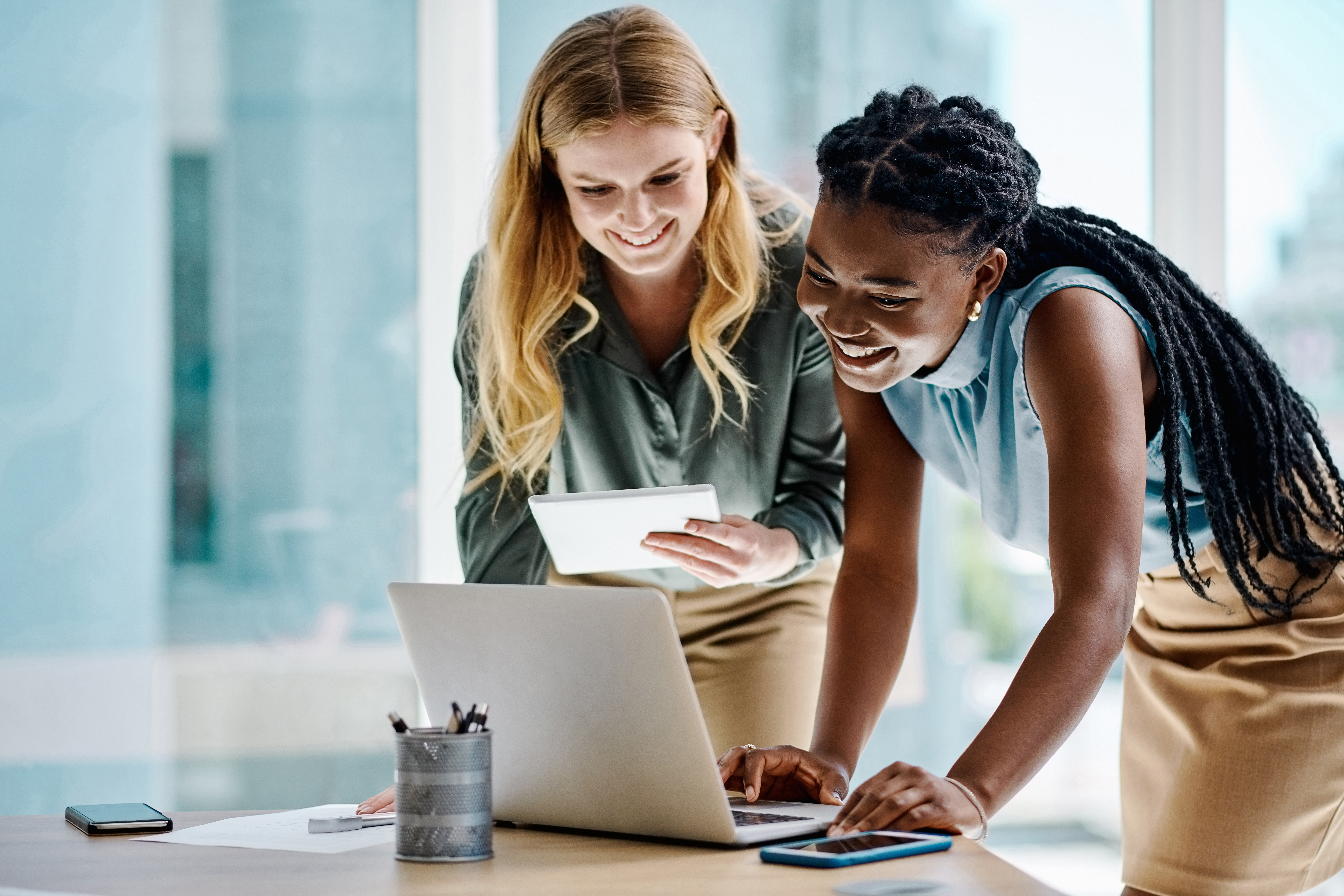 Employment contract concept. Two diverse businesswomen working together over open laptop.