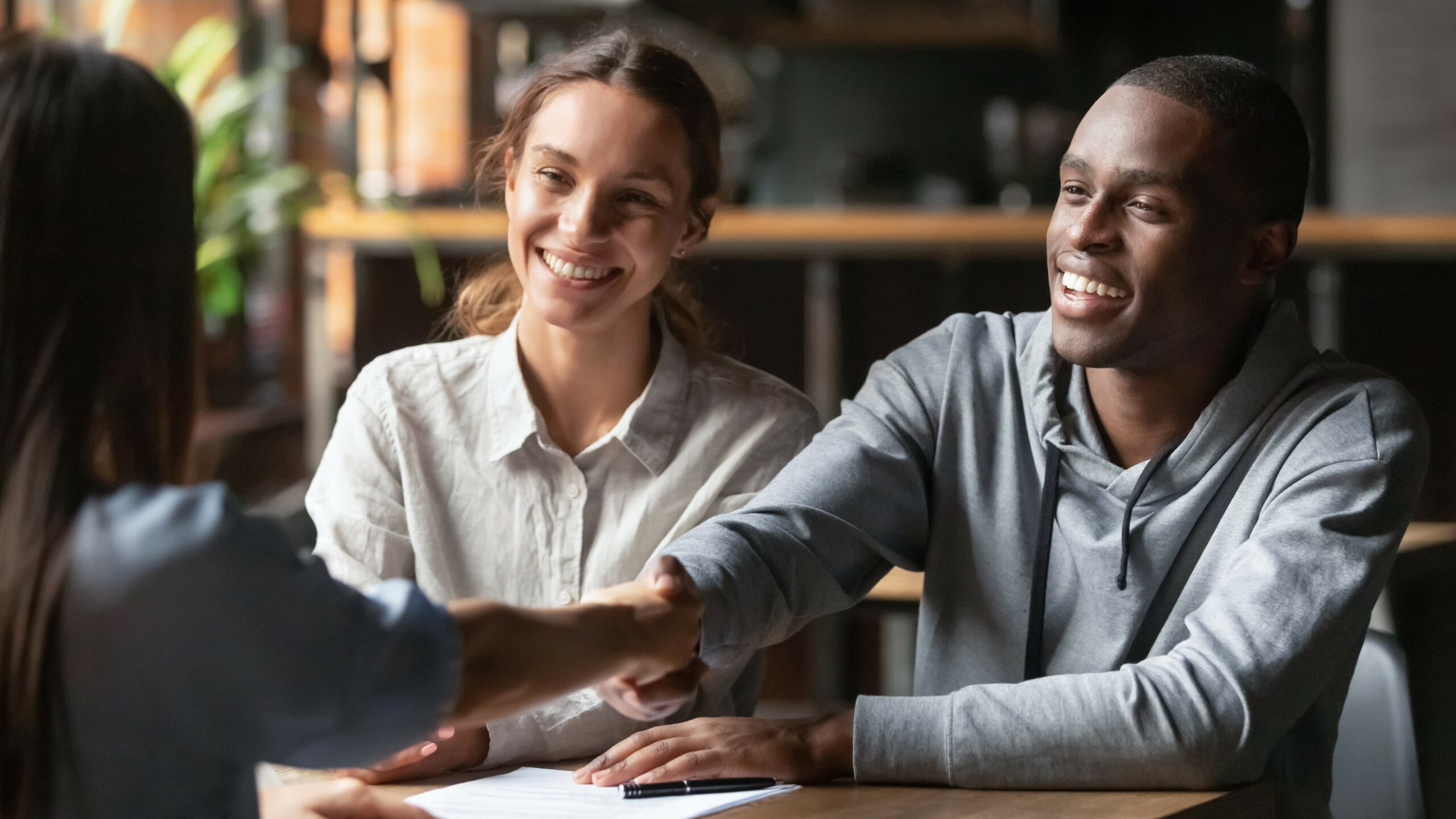 Interracial couple shaking hands with bank manager, business loan concept