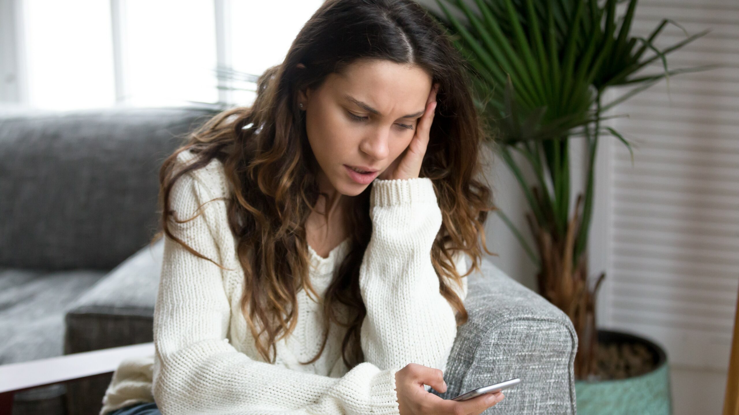 Woman reading something worrying on smartphone, threatening text concept