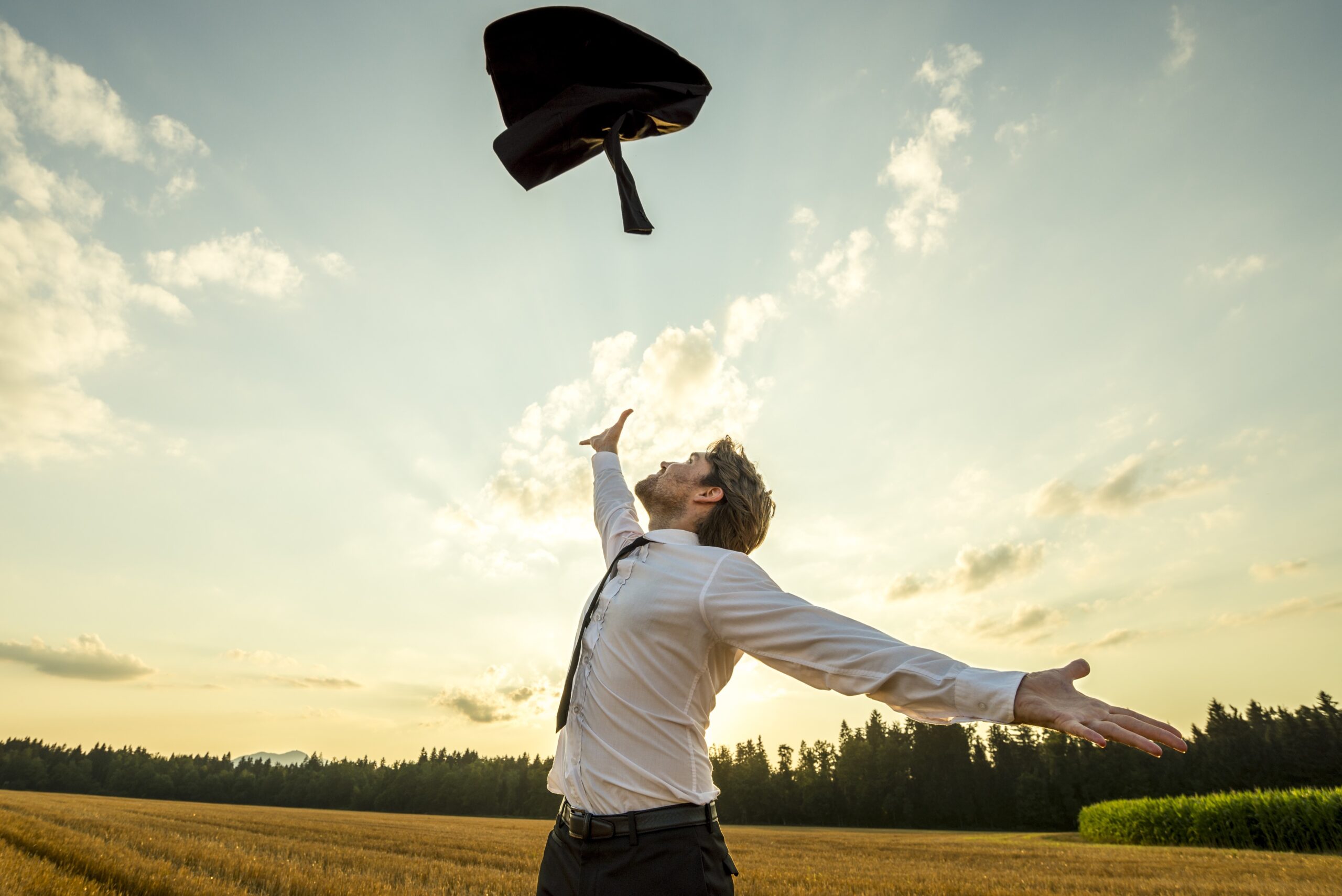 Businessman throwing away suit jacket in field, being self-employed concept