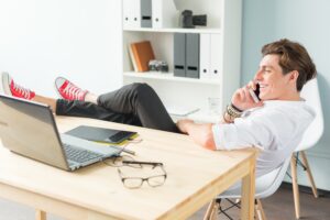 Young man on telephone with feet up on desk, exit strategy concept