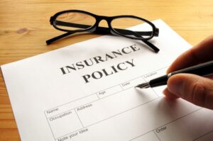 Employers' liability insurance concept. Hand signing insurance policy with glasses on contract