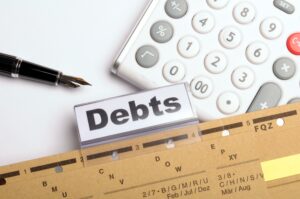 File with label Debts, calculator, pen, credit control concept