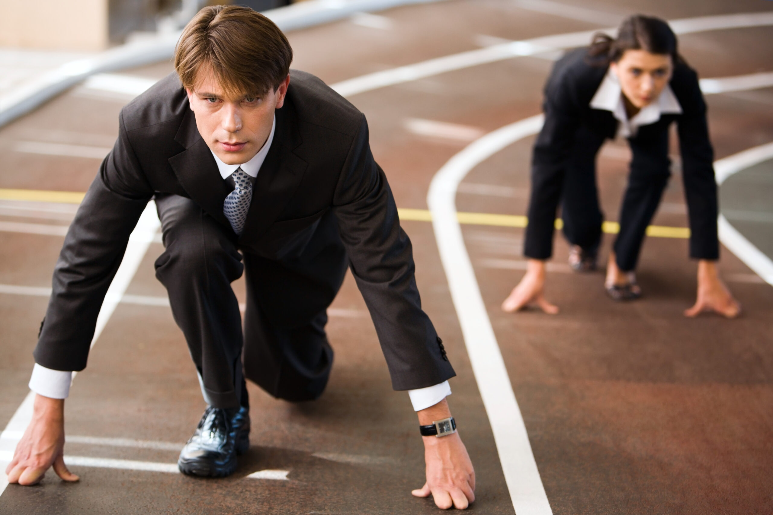 Businessman and businesswoman on starting blocks, competing business concept