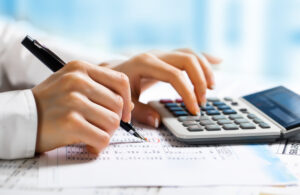 Man using calculator and amending figures by hand, accounting for start-ups concept