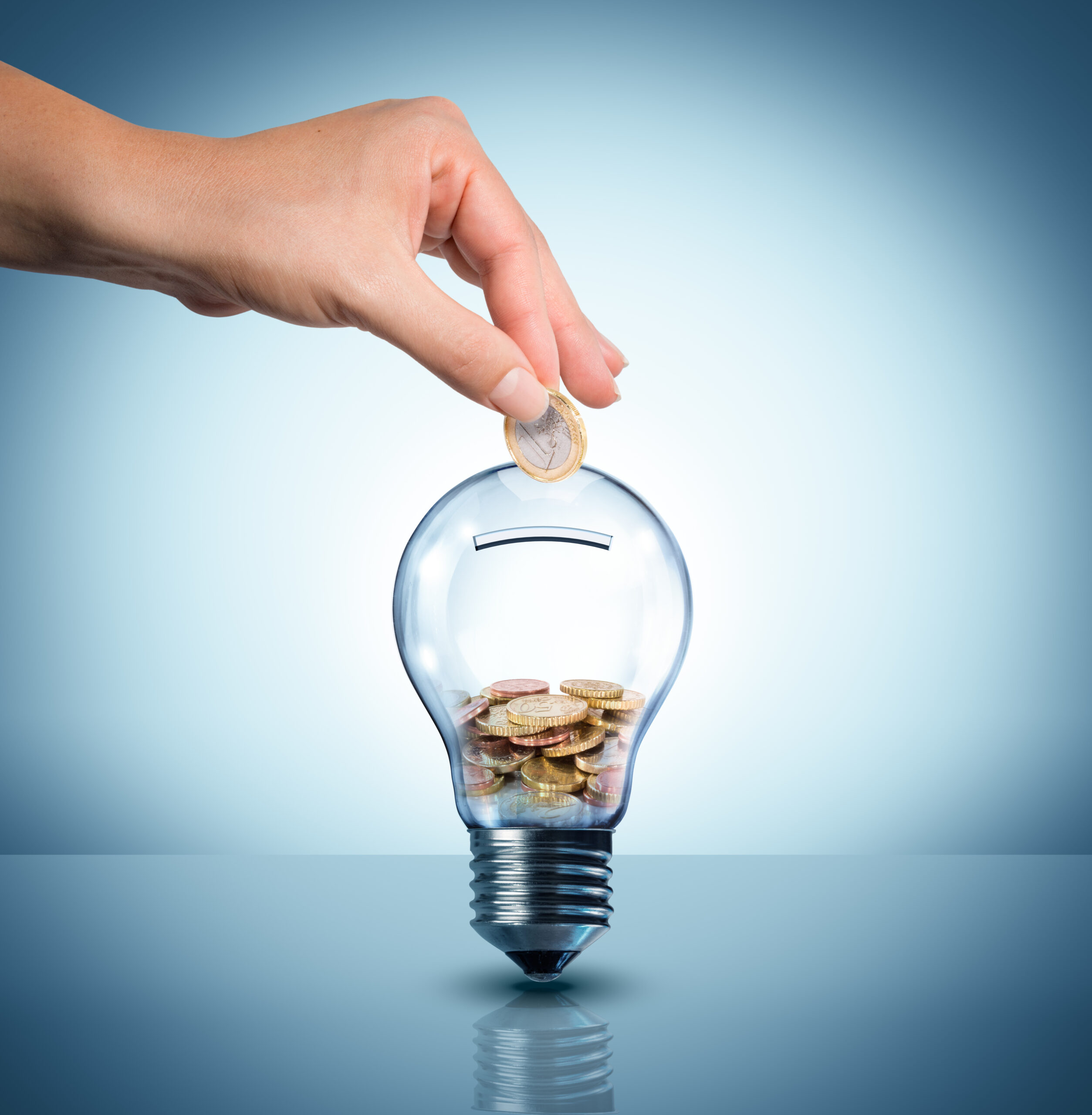 Hand putting coins in a lightbulb, smart meter concept