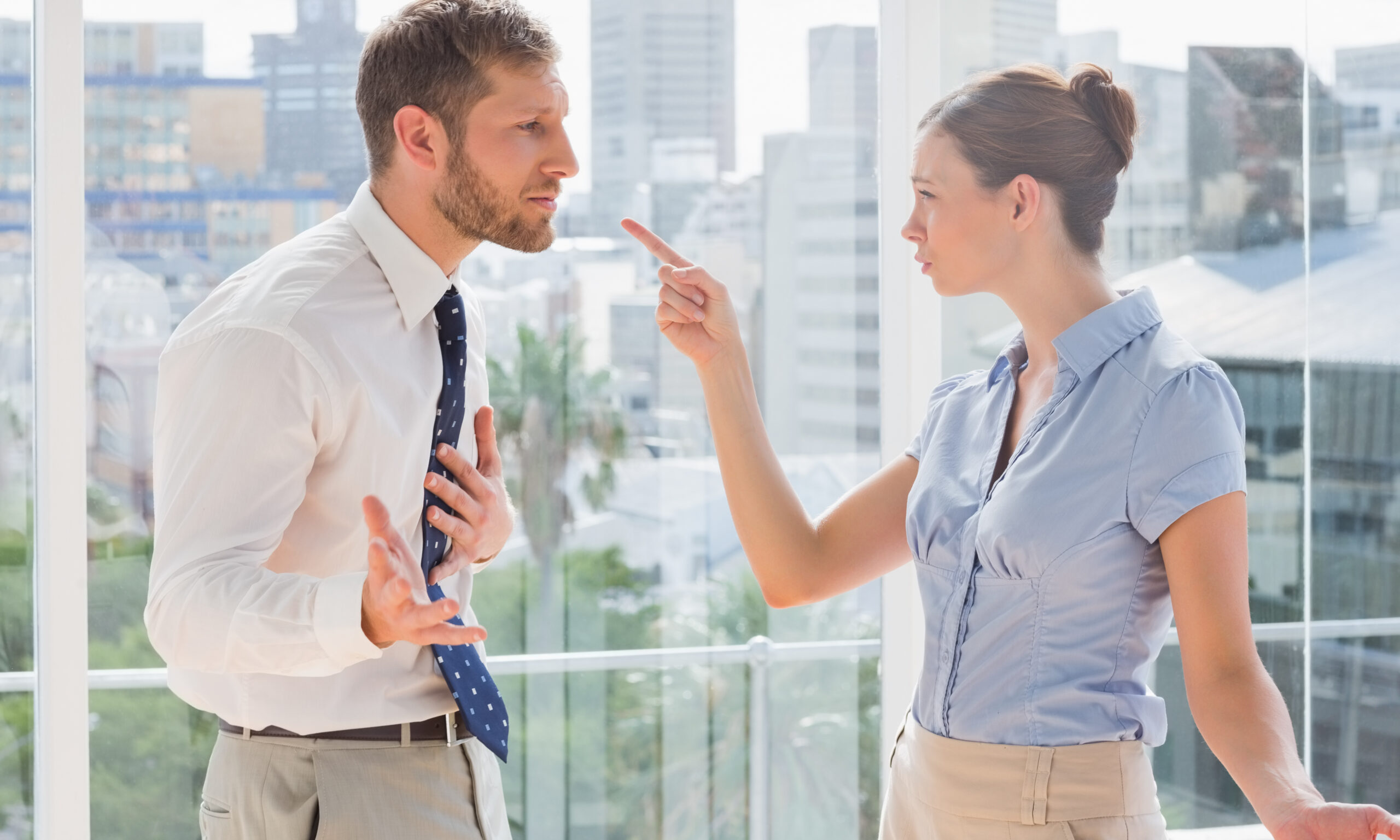 Business co-founders having a heated argument by large windows