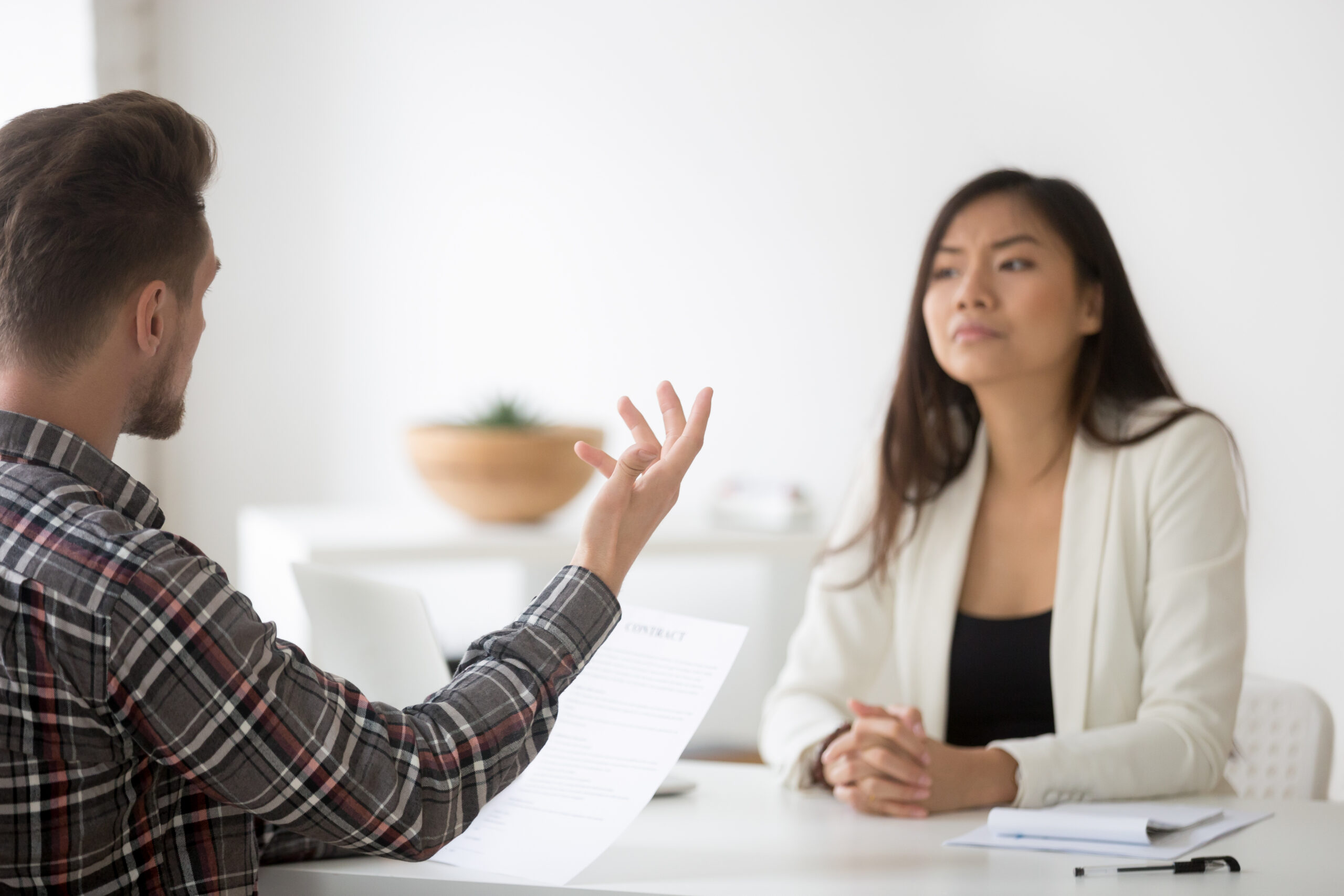 Unhappy employee confronting Asian woman