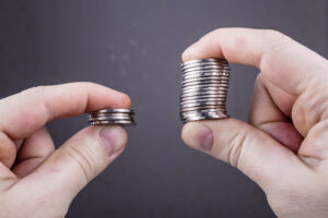 two stacks of coins in different hands being compared