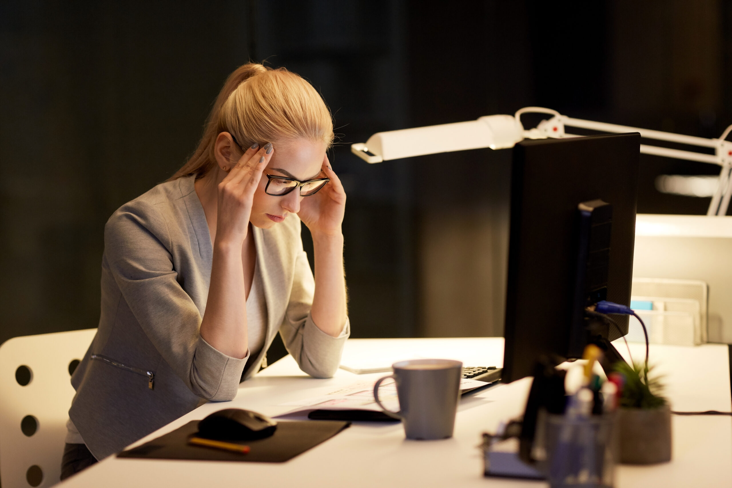Anxious woman sitting alone at desk at night, Brexit uncertainty concept
