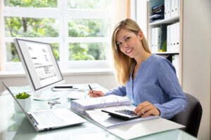 Young Businesswoman Calculating Bill With Computer And Laptop On Desk, UK small buisiness accountancy software concept