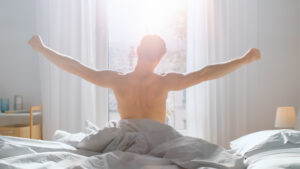 Man stretching getting out of bed, morning routine concept