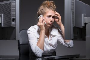 Tired and depressed woman at her workplace, hustle-and-grind concept