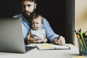 Father with a baby on his lap trying to work, pivoting to an online business concept