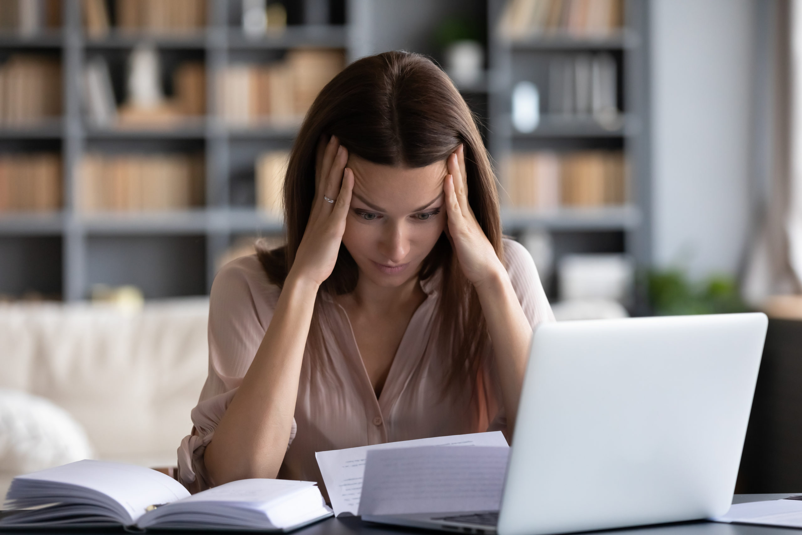 Stressed businesswoman head in hands looking at laptop, staff reduced hours concept