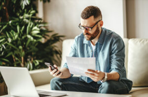 bearded man sitting on sofa in front of laptop, freelance UK concept