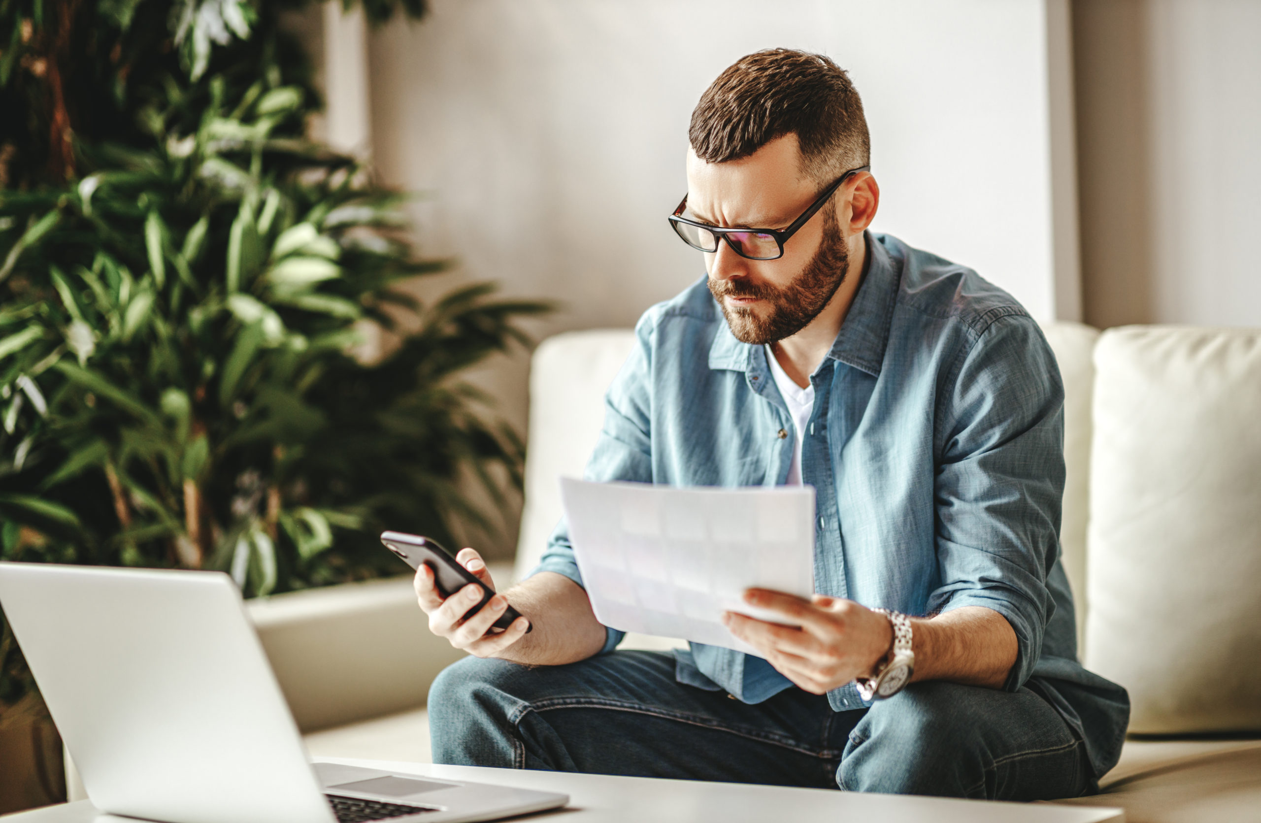 bearded man sitting on sofa in front of laptop, freelance UK concept