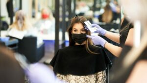 Woman having hair coloured in hairdressers wearing facemask, reopen hairdressers concept