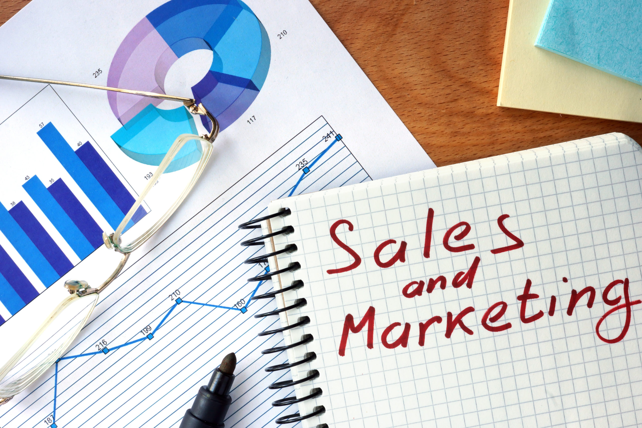 Notepad with Sales and Marketing concept on a wooden board, small business marketing 101 concept