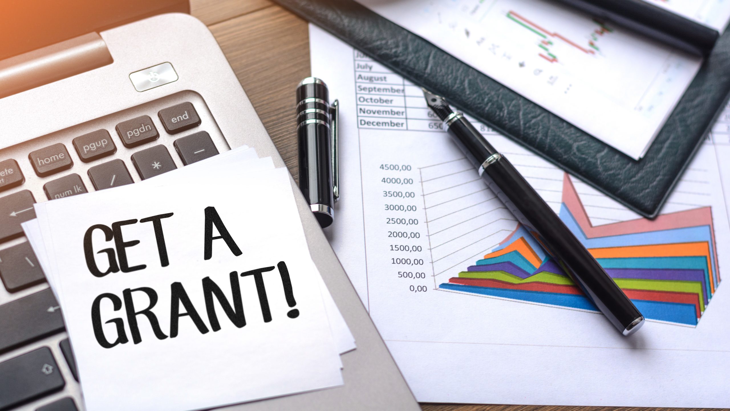 'Get a Grant!' note on top of calculator, small business technology grant concept