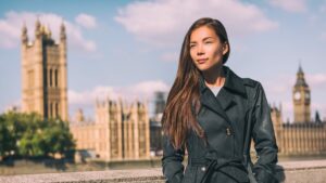 Asian woman standing in front of House of Commons, Westminster Palace, self-employed national insurance concept