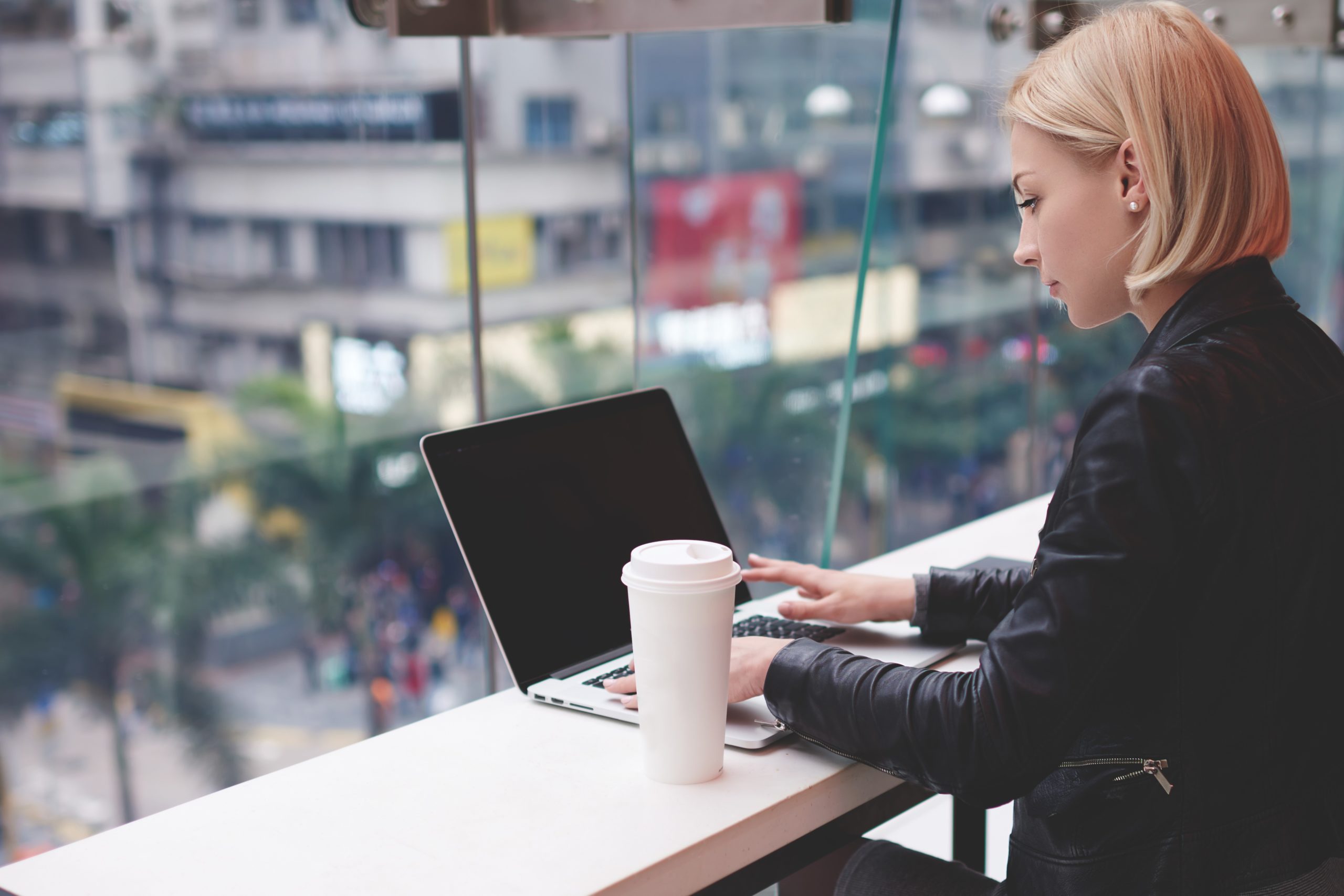 Young woman working on laptop in modern cafe, self-employed universal credit concept