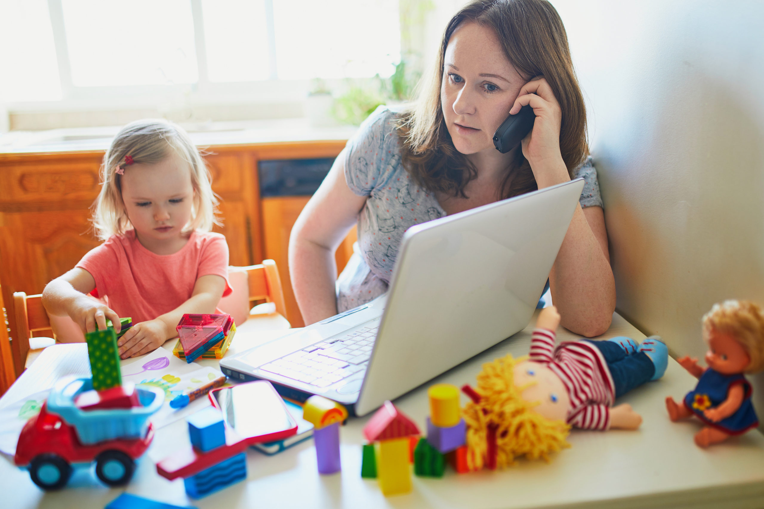 Stresseed mother on mobile working from home with toddler, self-employed 50% concept