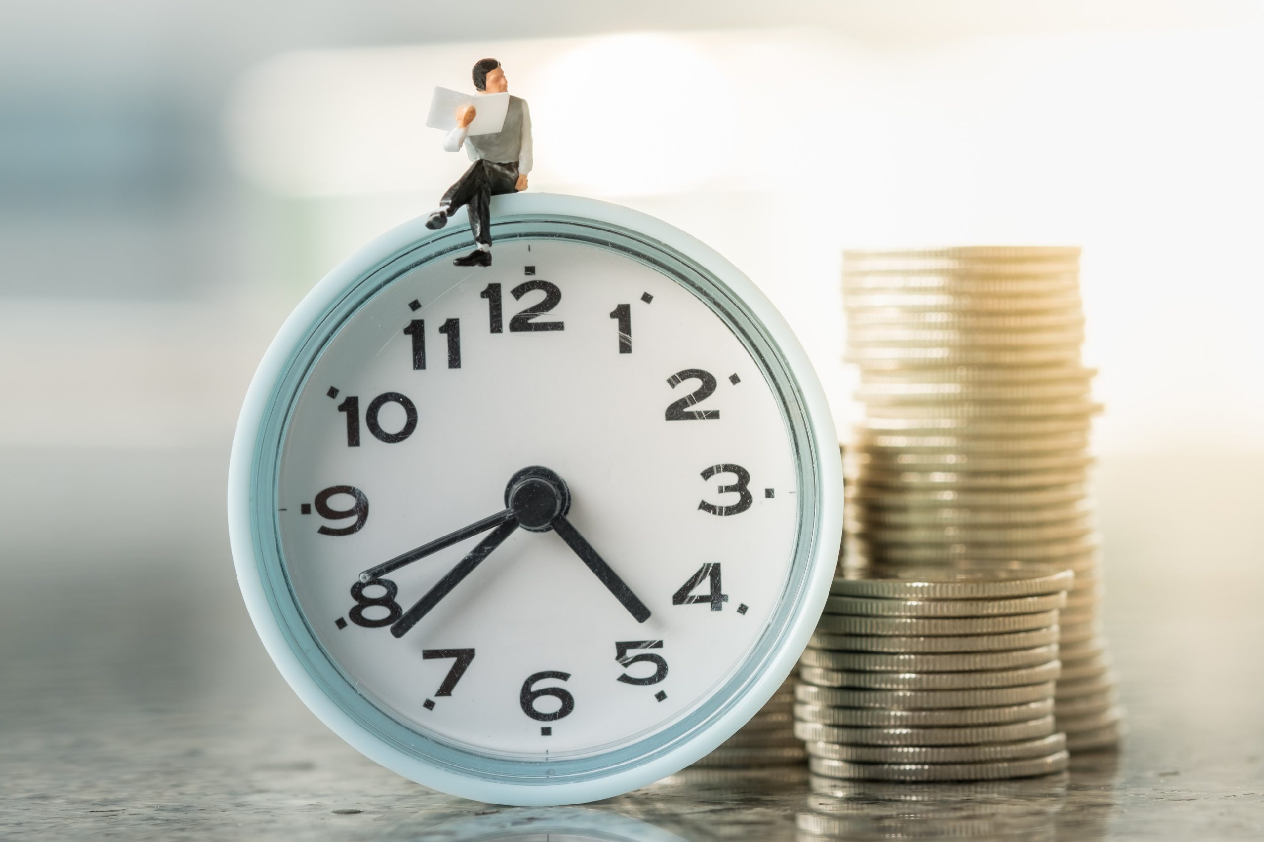 Tiny man sitting on alarm clock with pile of coins, Covid-19 grants concept