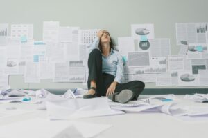 Stressed businesswoman sitting on floor surrounded by printouts, businesses collapse support concept