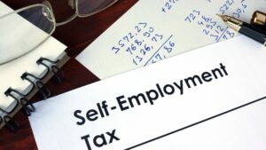 Words Self-Employment Tax on sheet of paper with calculations in fountain pen, self-employed tax concept