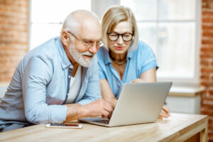 Happy older couple bent over laptop, older customers concept
