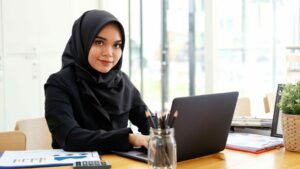 Muslim businesswoman sitting in front of laptop, Islamic finance concept