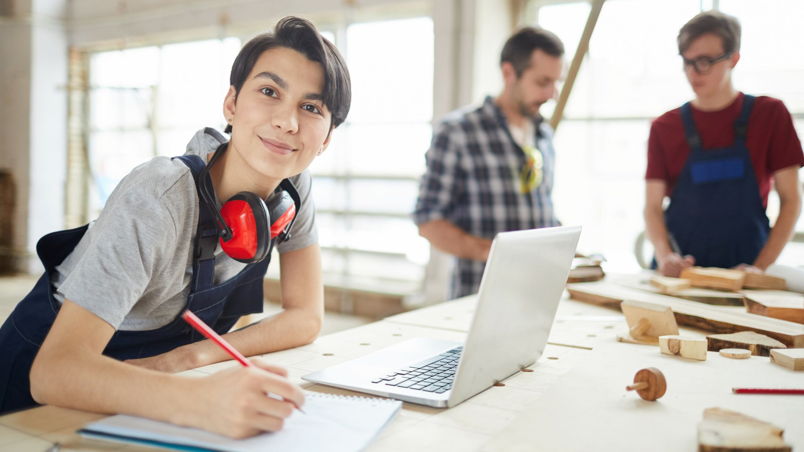 young woman at laptop in carpentry workshop, T Level concept