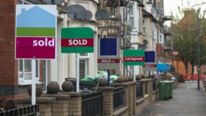 Estate agent sale boards outside terraced street, property company concept