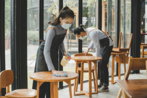 Waiters cleaning tables in cafe, Covid safe concept