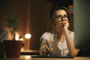 Young bespectacled woman concentrating on Mac screen, professional indemnity insurance concept