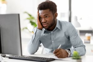 stressed black businessman looking at computer monitor, finances concept