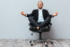 Man sitting cross-legged in office chair in yoga pose, office chair concept