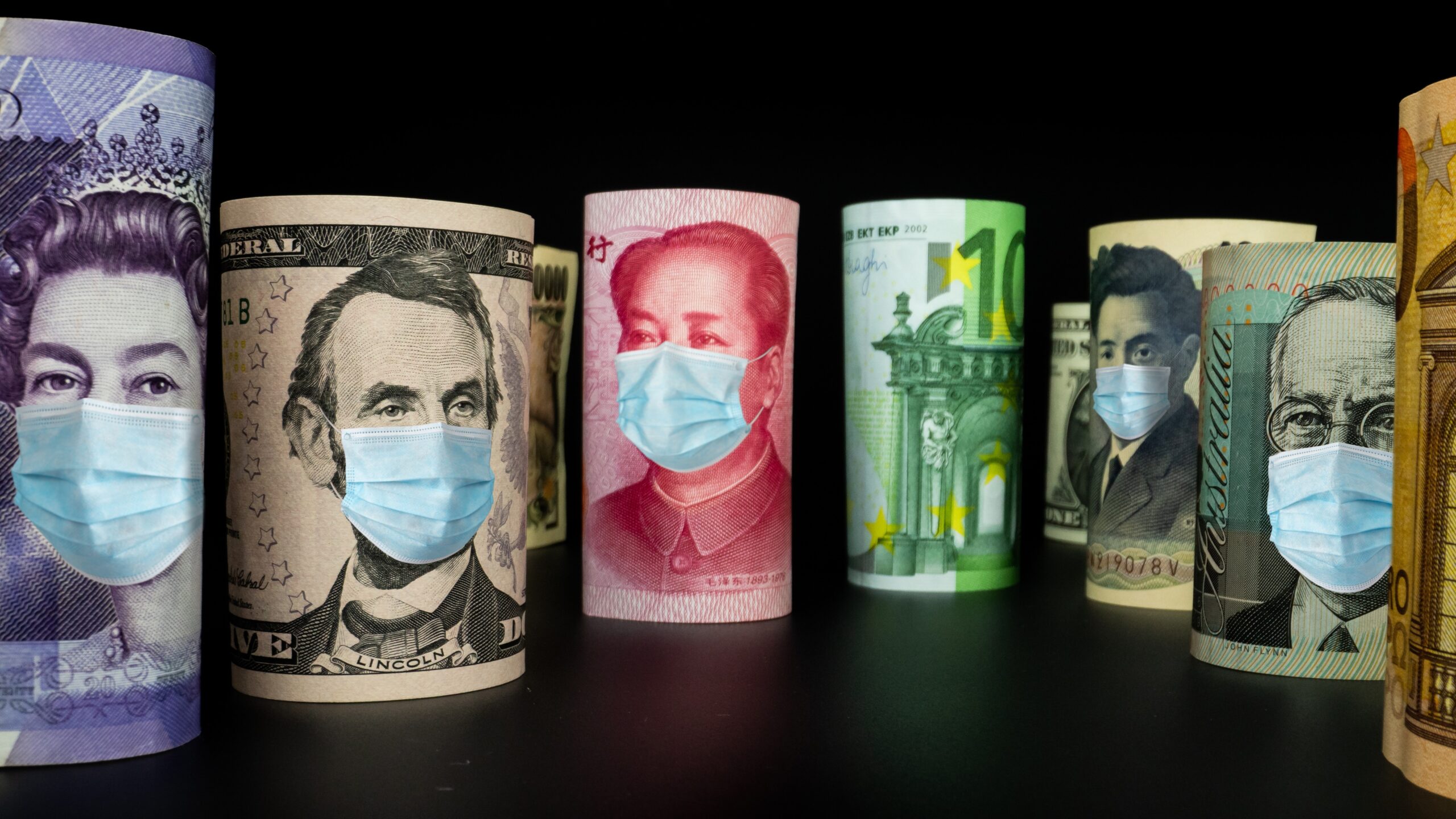 Rolled international currency banknotes wearing facemasks, recovery loan scheme concept