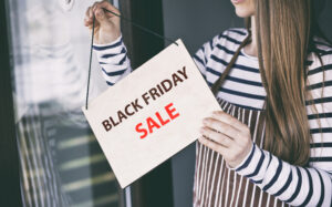 Woman adjusting 'Black Friday Sale' sign, Black Friday 2021 concept
