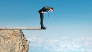 Young office worker standing on cliff-edge diving board, self-employed concept
