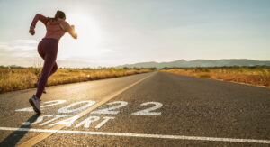 Woman sprinting over 2022 start sign on road, starting a new business concept