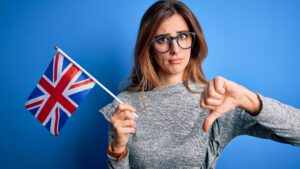 Young woman waving Union Jack flag giving thumb down, Brexit deal concept