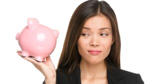 Woman looking unamused at piggy bank, bounce back loan concept