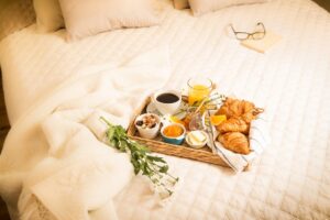 Continental breakfast on bed in elegant bedroom interior.