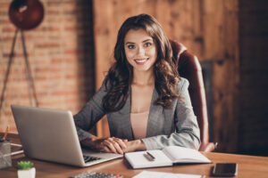 Young woman sitting at desk behind laptop, setting up a business concept