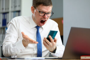 Angry young businessman in tie shouting at mobile phone