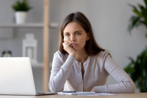 Young woman looking unhappy at laptop, jobs concept
