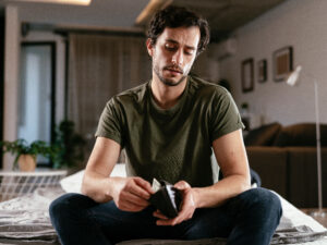 Sad young man checking empty wallet, self-employed concept