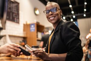 Smiling woman using smartphone to pay in restaurant, payment apps small businesses concept